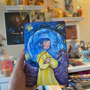 May include: A hand-painted canvas featuring a girl with blue hair wearing a yellow raincoat standing in front of a large blue moon with a starry night sky background. The painting is signed "MCC" in the bottom right corner.