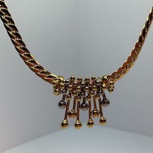 May include: A gold chain necklace with a pendant made of gold and silver beads. The pendant is shaped like a cluster of small balls.