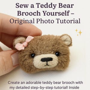May include: A handmade brown teddy bear brooch with a light pink bow. The brooch has black eyes and a black nose. The text on the image says "Sew a Teddy Bear Brooch Yourself - Original Photo Tutorial".