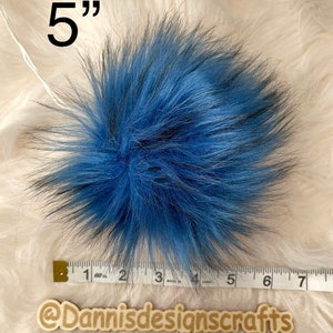 Peut inclure: Un pompon en fausse fourrure bleu et noir de 5 pouces. Le pompon est pr&eacute;sent&eacute; &agrave; c&ocirc;t&eacute; d'une r&egrave;gle pour r&eacute;f&eacute;rence de taille.