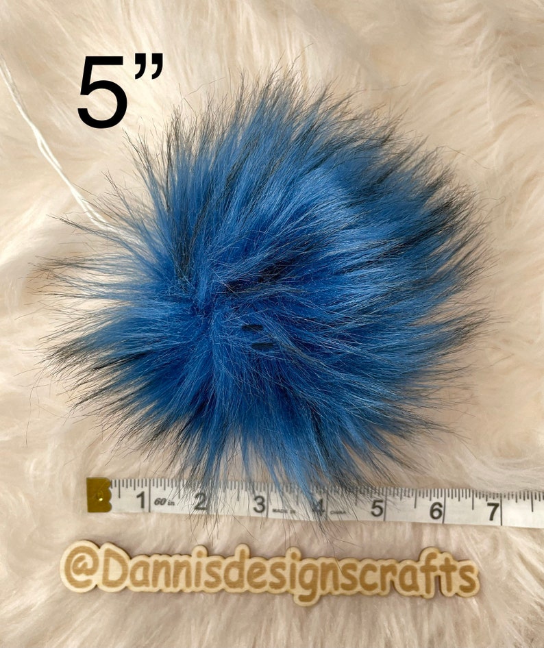 Peut inclure: Un pompon en fausse fourrure bleu et noir de 5 pouces. Le pompon est pr&eacute;sent&eacute; &agrave; c&ocirc;t&eacute; d'une r&egrave;gle pour r&eacute;f&eacute;rence de taille.