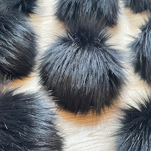 May include: A collection of black faux fur pom poms. The pom poms are soft and fluffy, and they would be perfect for adding a touch of luxury to any project.