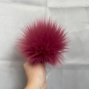 May include: A large, fluffy, pink pom pom made of faux fur.
