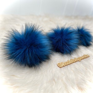 Peut inclure: Trois pompons en fausse fourrure bleue sur une surface blanche et moelleuse. Les pompons sont doux et moelleux et seraient parfaits pour ajouter une touche de couleur &agrave; un chapeau ou une &eacute;charpe.