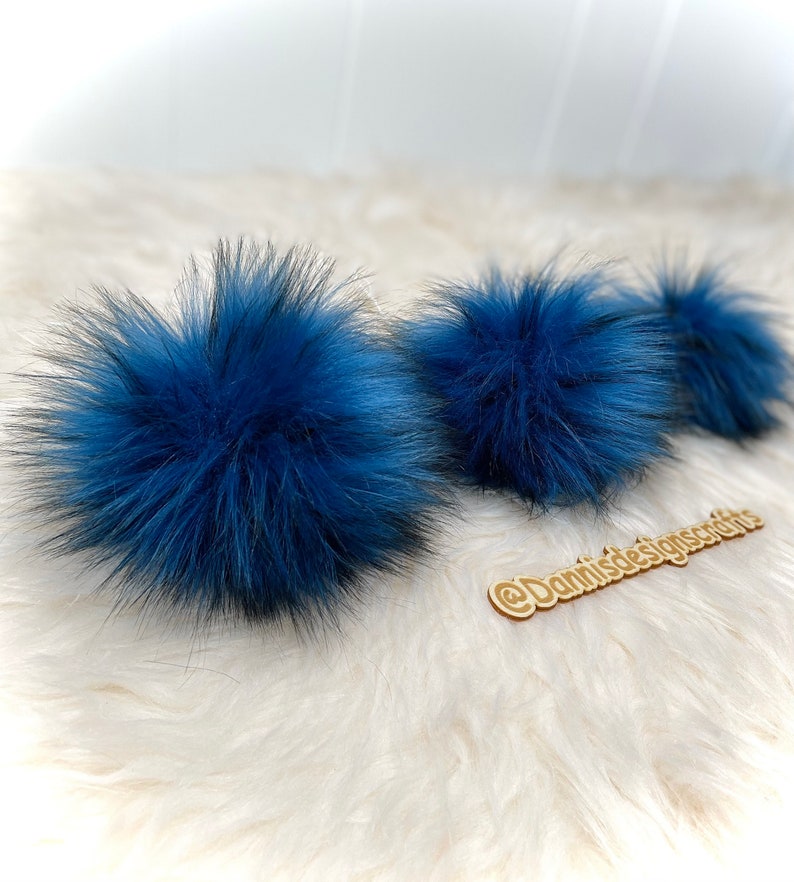 Peut inclure: Trois pompons en fausse fourrure bleue sur une surface blanche et moelleuse. Les pompons sont doux et moelleux et seraient parfaits pour ajouter une touche de couleur &agrave; un chapeau ou une &eacute;charpe.