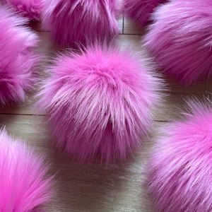 May include: A collection of pink fluffy pom poms. The pom poms are soft and plush, and they would be perfect for adding a touch of whimsy to any project.