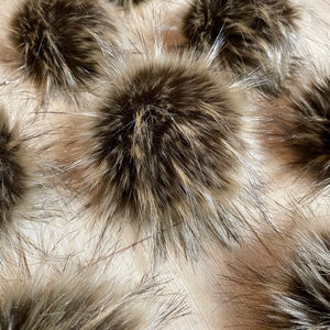 May include: A collection of brown faux fur pom poms. The pom poms are fluffy and have a soft texture.