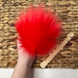 May include: A bright red fluffy pom pom, perfect for adding a pop of color to crafts and projects.  @DanMadeDesignscrafts