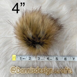 May include: A 4 inch brown and black faux fur pom pom. The pom pom is measured with a tape measure.