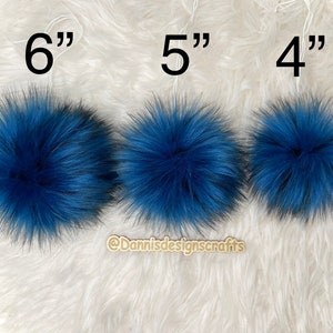 Peut inclure: Trois pompons en fausse fourrure bleue de diff&eacute;rentes tailles, 15 cm, 13 cm et 10 cm de diam&egrave;tre. Les pompons sont pr&eacute;sent&eacute;s sur une surface blanche et moelleuse.