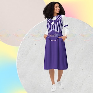 Puede incluir: Un vestido morado con un chaleco superpuesto de rayas blancas y negras. El vestido tiene bolsillos a los lados y un detalle de corbata de lazo. El vestido es de largo hasta la rodilla y tiene una falda acampanada. La modelo lleva zapatillas blancas.