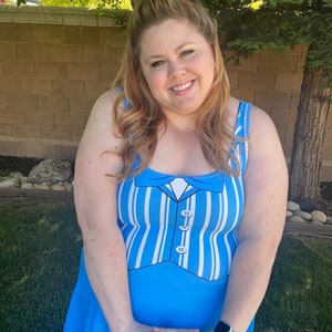 May include: A woman wearing a blue and white striped dress with a white bow tie and buttons. The dress has a skirt that flares out.