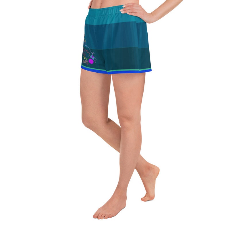 May include: A pair of blue and green athletic shorts with a colorful graphic print. The shorts have a wide elastic waistband and a relaxed fit.