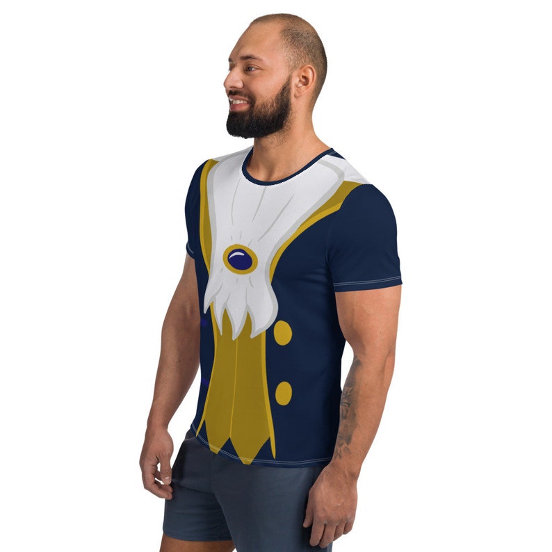 May include: A navy blue t-shirt with a printed design of a gold and white prince costume. The costume features a white collar, gold buttons, and a blue gem.