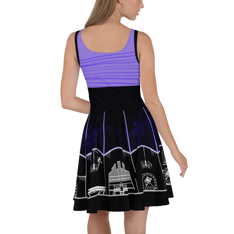May include: A purple and black skater dress with a white silhouette of a haunted house and other spooky attractions. The dress has a purple striped bodice and a black skirt with a white silhouette of a haunted house and other spooky attractions.
