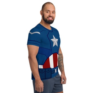 May include: A blue t-shirt with a white star and red, white, and blue stripes. The shirt has a design that looks like a superhero costume.