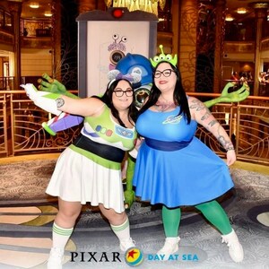May include: Two people dressed as characters from the movie Toy Story. One person is dressed as Buzz Lightyear and the other is dressed as an alien. They are standing in front of a wall with a Pixar Day at Sea logo.