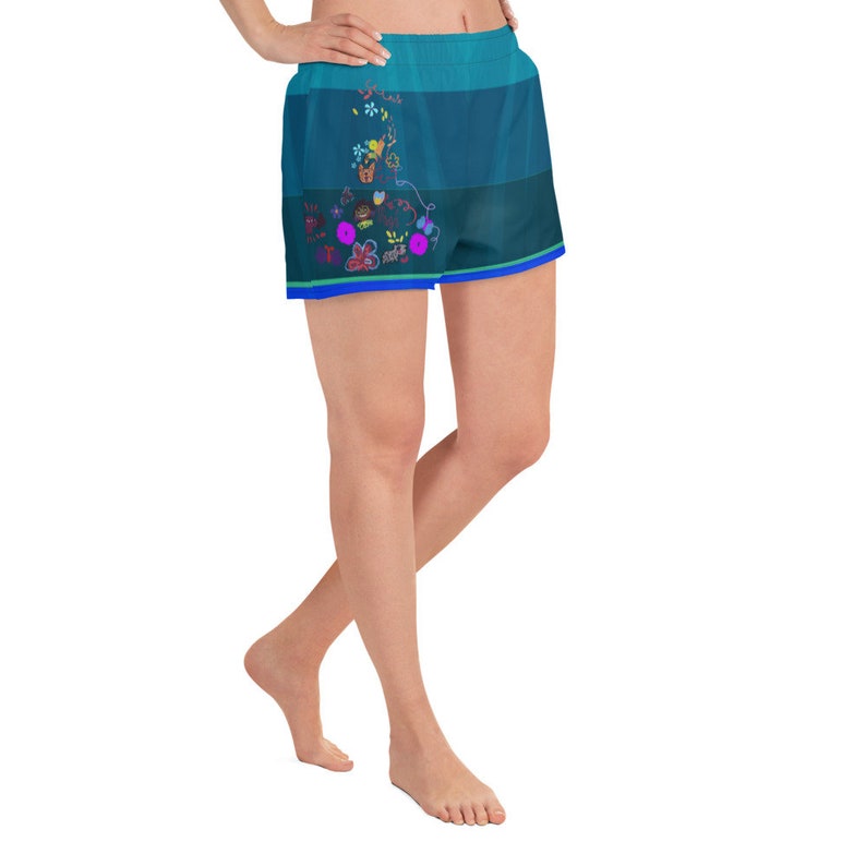 May include: A woman wearing blue and green athletic shorts with a floral design. The shorts have a blue waistband and a blue trim around the legs.