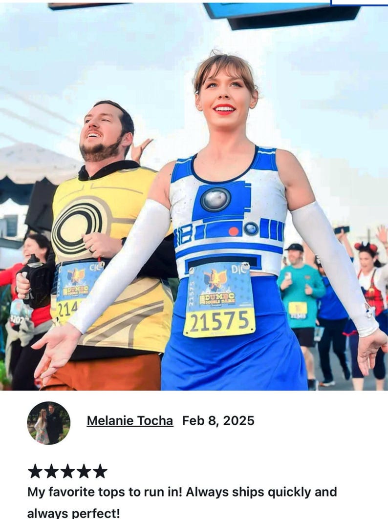 May include: Two people wearing running outfits with race numbers. The woman is wearing a blue and white R2-D2 themed running top and a blue skirt. The man is wearing a yellow running top with a circular design. The woman's race number is 21575 and the man's race number is 214.