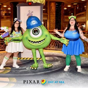 May include: Two people dressed as characters from the Pixar movie Monsters Inc. and Toy Story. One person is dressed as Mike Wazowski, the green one-eyed monster, and the other is dressed as a character from Toy Story. The background is a cruise ship with gold accents. The text "PIXAR DAY AT SEA" is visible at the bottom of the image.
