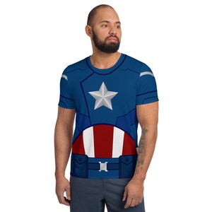 May include: A blue and red t-shirt with a white star and a red, white, and blue shield design. The shirt is a superhero costume.
