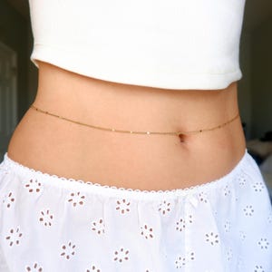 Peut inclure: Une fine cha&icirc;ne de taille dor&eacute;e au design minimaliste compos&eacute; de maillons m&eacute;talliques uniformes. La cha&icirc;ne repose horizontalement autour de la taille, formant une ligne continue et subtile qui souligne la silhouette avec &eacute;l&eacute;gance.