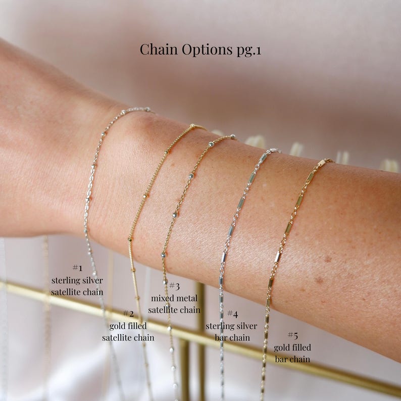 May include: A display of five delicate chain necklaces. The chains are silver and gold, with various designs including satellite and bar styles. The text "Chain Options pg.1" is at the top, with labels for each chain type.