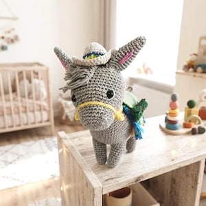 Detailed close-up of a handmade crochet donkey toy showing its cute face, floppy ears, and miniature sombrero hat.