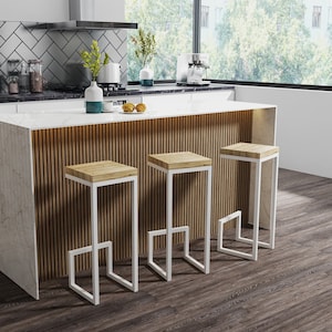 Op de afbeelding: Drie witte metalen barstoelen met houten zittingen in een moderne keuken. De stoelen staan voor een keukeneiland met een wit aanrechtblad en een achterwand van houten panelen.