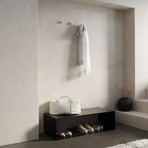 Può includere: Una moderna scena d'ingresso con una panca nera con porta scarpe, una borsa da viaggio bianca e una sciarpa colorata appesa a ganci a muro. Un vaso nero decorativo con rami e una parete dai toni neutri completano il design minimalista.