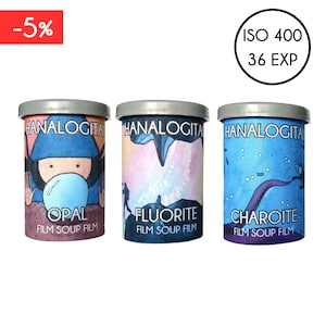 Può includere: Tre cartucce di pellicola da 35 mm con illustrazioni colorate e il testo "HANALOGITAL FILM SOUP FILM" su ciascuna. Le cartucce sono etichettate "OPAL", "FLUORITE" e "CHAROITE".