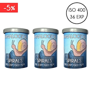 Può includere: Tre contenitori di pellicola blu con coperchi grigi. Ogni contenitore presenta un'illustrazione di lumaca e il testo "ANALOGITAL SPIRALS PRE-EXPOSED FILM". I contenitori hanno anche il testo "ISO 400 36 EXP".