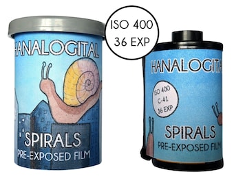 May include: A cylindrical container and a 35mm film canister labeled HANALOGITAL SPIRALS PRE-EXPOSED FILM. Both feature a blue sky illustration with a snail on a city skyline. The text ISO 400 36 EXP is visible on the container and the film canister.