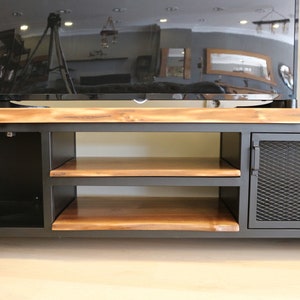 May include: A black metal TV stand with two shelves and two doors. The doors have a wire mesh design. The top of the stand is made of wood.