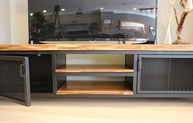 May include: A black metal TV stand with two shelves and two doors. The doors have a wire mesh design. The top of the stand is made of wood.