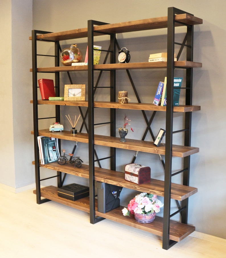 Pode incluir: Uma estante alta de estilo industrial com estrutura de metal preto e prateleiras de madeira. As prateleiras est&atilde;o cheias de v&aacute;rios itens, incluindo livros, plantas e objetos decorativos.