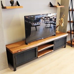 May include: A black metal TV stand with a wooden top and two doors. The stand has a shelf and is made of reclaimed wood.