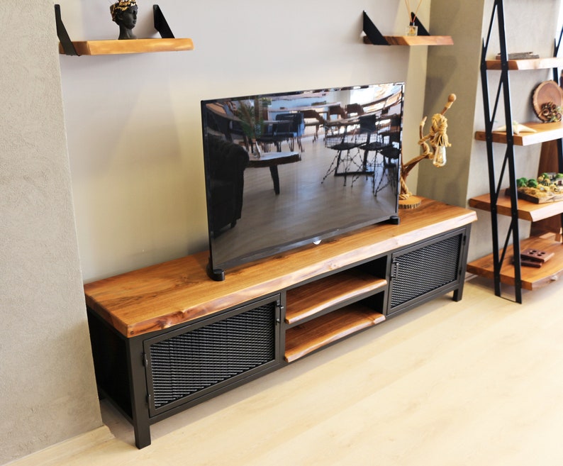 May include: A black metal TV stand with a wooden top and two doors. The stand has a shelf and is made of reclaimed wood.