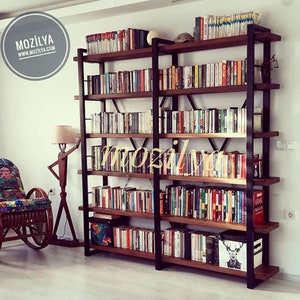 Pode incluir: Uma estante alta de metal preto com prateleiras de madeira cheias de livros. A estante tem um design industrial moderno e &eacute; perfeita para exibir uma grande cole&ccedil;&atilde;o de livros.