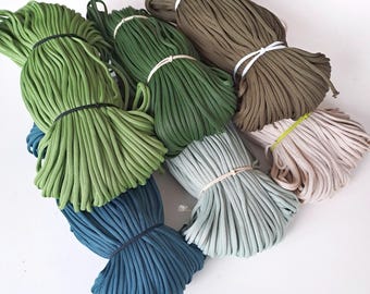 May include: Bundles of colorful nylon cord in shades of green, blue, and tan, secured with rubber bands. The cords are tightly wound, showcasing a variety of hues, from light green to deep teal and olive. Ideal for crafting and DIY projects.