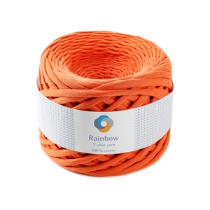 May include: A ball of orange T-shirt yarn, with a white label wrapped around it. The label reads "Rainbow T-shirt yarn 100% cotton". The yarn is tightly wound, displaying its texture and colour. Ideal for crafting projects.