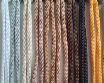 May include: A color chart of 11 different shades of cord, ranging from white to yellow. The cords are arranged in a row, with the numbers 1 through 11 printed above each cord.