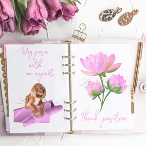 May include: An open planner with two pages. The left page has a pink illustration of a dog on a pink blanket with the text "Dog pose with an expert". The right page has a pink illustration of a flower with the text "Think positive".