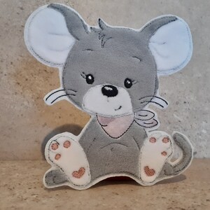 Könnte beinhalten: Graue Filz-Maus-Applikation mit weißen Ohren und Pfoten sowie einer rosa Schleife. Die Maus hat schwarze Augen und Schnurrhaare. Die Applikation ist zum Aufnähen auf Kleidung oder andere Stoffartikel gedacht.