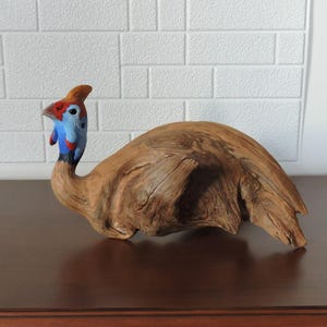 Helmeted guineafowl, a bird sculpture, a wooden bird.