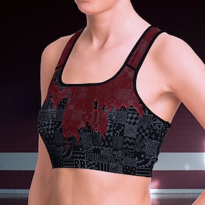 Op de afbeelding: Een zwarte en rode sportbeha met een geometrisch patroon. De beha heeft een racerback-stijl en is gemaakt van een rekbaar, ademend materiaal.