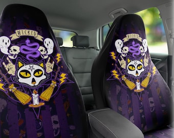 May include: A pair of black car seat covers with a purple and black design featuring a cat with a skull face, a snake, and the word "WICKED".