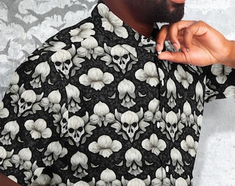 Pode incluir: Uma camisa preta de manga curta com botões e um padrão de caveiras e flores brancas.