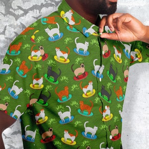 May include: A green button-down shirt with a repeating pattern of cats riding skateboards. The cats are in various colors, including white, black, brown, and orange. The skateboards are all black with white wheels.