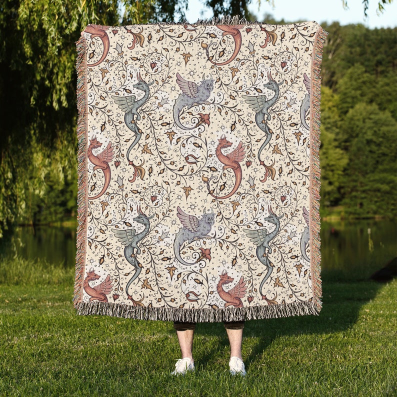 May include: A woven throw blanket with a cream background and a repeating pattern of stylized dragons and vines. The dragons are in shades of blue, pink, and green.